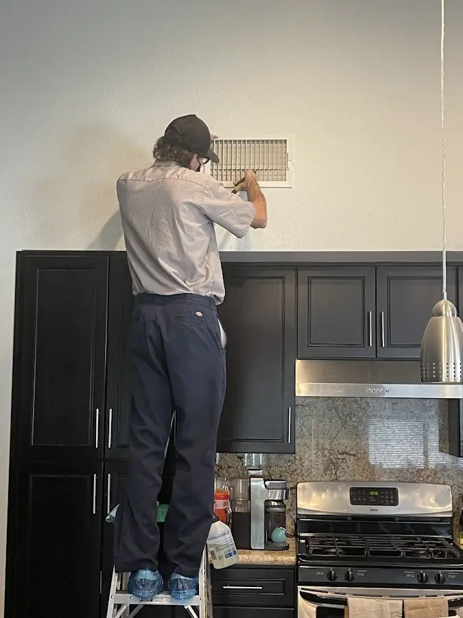 Technician inspecting an air vent during HVAC service in Keller